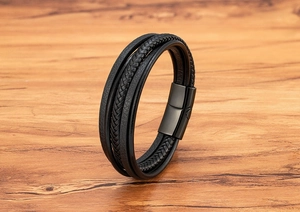 Close-up of multi-layer black leather bracelet with magnetic metal clasp on wood