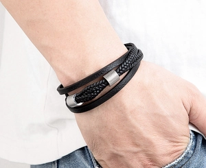 Detailaufnahme des mehrlagigen schwarzen Lederarmbands mit silbernen Metallakzenten am Handgelenk