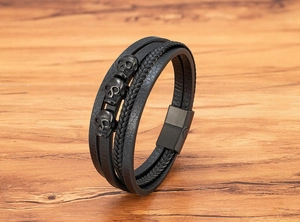 Nahaufnahme von mehrlagigem Herren-Lederarmband mit drei Totenkopf-Anhängern aus Metall