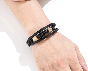 Detailansicht eines mehrlagigen schwarzen Lederarmbands mit goldfarbenen Metall-Zylinderperlen