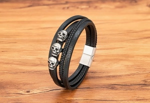 Detail eines mehrlagigen schwarzen Lederarmbands für Herren mit Totenköpfen und Magnetverschluss