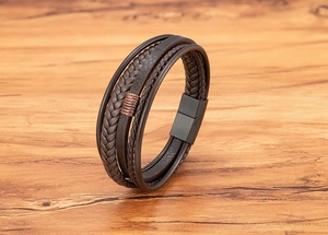 Close-up of multi-layer brown leather bracelet with braided cords and magnetic metal clasp