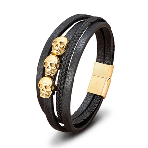 Nahaufnahme eines mehrlagigen schwarzen Lederarmbands mit goldenen Totenköpfen und Magnetverschluss