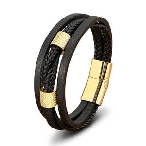 Detail eines mehrlagigen schwarzen Lederarmbands mit goldenen Metallzylindern und Magnetverschluss