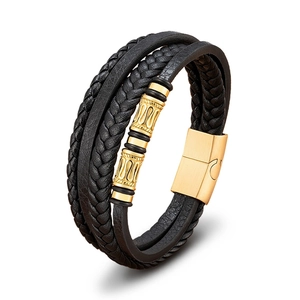 Vista detallada de la pulsera de cuero negro trenzado con cilindros de metal dorado