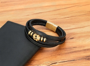 Close-up of multilayer leather bracelet with golden skull charm and magnetic clasp