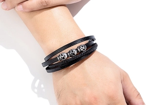Nahaufnahme von mehrlagigem Lederarmband mit silbernen Totenköpfen am Herrenhandgelenk