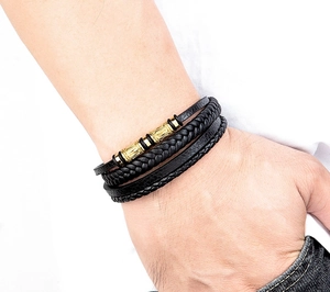 Detalle macro de la pulsera de cuero de triple capa con tubos metálicos dorados grabados