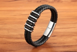 Dettaglio del bracciale in pelle nera intrecciata con anelli in acciaio inossidabile e chiusura