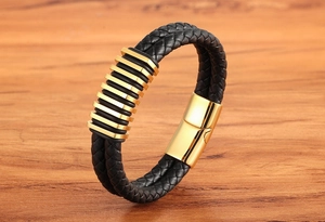 Dettaglio macro del bracciale da uomo in pelle nera intrecciata con anelli d'oro e chiusura