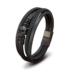 Detail of multi-layer black leather bracelet with metal skull and magnetic clasp