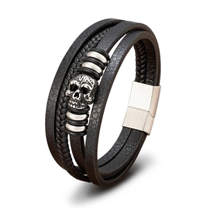 Close-up of multilayer leather bracelet with silver skull charm and magnetic steel clasp