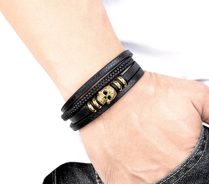 Detail of multi-layer leather bracelet featuring golden skull and stainless steel magnet clasp
