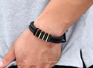 Dettaglio del bracciale da uomo in pelle intrecciata a doppio strato con barre in oro