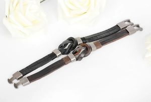 Close-up of black and brown leather braided bracelets with vintage silver alloy clasps