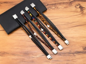 Primo piano di quattro bracciali multistrato da uomo in pelle con pietre naturali e croce