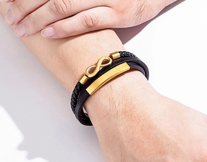 Makro-Detail von Herren Lederarmband, schwarz geflochten mit goldenem Unendlichkeitssymbol
