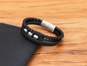 Herren-Lederarmband mit matten Perlen und silbernem Magnetverschluss auf einem Holztisch