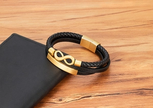 Detail eines geflochtenen schwarzen Lederarmbands mit goldenem Unendlichkeitssymbol