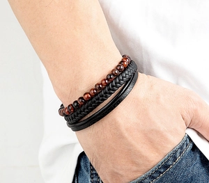 Detail of men's layered leather bracelet with red tiger eye beads on person's wrist