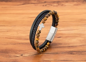 Dettaglio di un bracciale in pelle multistrato con pietre occhio di tigre e croce