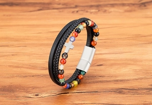 Dettaglio del bracciale multistrato in perle di pietra con croce argentata su legno