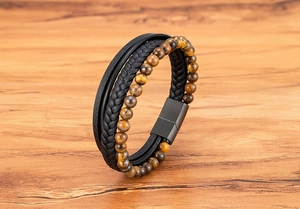 Detail of multi-layer men's bracelet featuring braided black leather and tiger eye beads