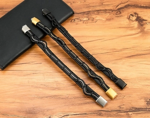 Detail of three braided leather bracelets for men with silver, gold, and black magnetic clasps