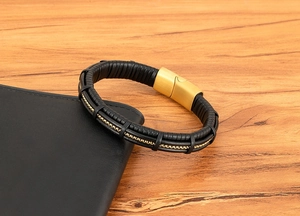 Close-up of woven black leather men's bracelet with gold chain inlay and matte metal clasp