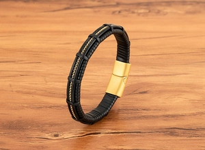 Detail of black woven leather bracelet for men featuring a gold chain inlay and magnetic clasp