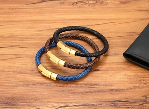 Close-up of three braided leather bracelets in black, brown, and blue with gold metal buckles