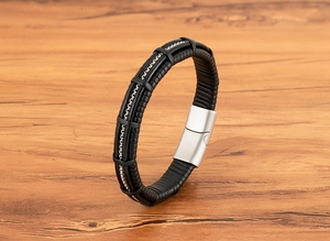 Close-up of black multi-layer leather bracelet with silver metal chain on wood texture