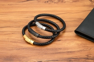 Close-up of men's braided leather bracelets with matte silver, gold, and black magnetic clasps