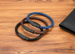 Detail van gevlochten leren armbanden in blauw, bruin en zwart met getextureerde sluitingen