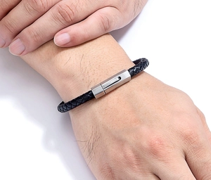 Detailed close-up of a men's black braided leather bracelet with a brushed steel clasp