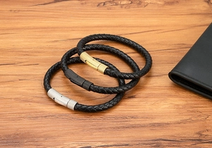 Detail van gevlochten leren armbanden met magnetische sluitingen op een houten tafel