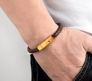 Close-up of men's brown braided leather bracelet featuring a sleek matte gold hexagonal clasp