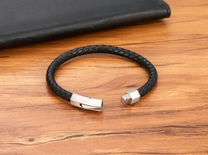 Detail shot of the silver magnetic clasp on a black braided leather bracelet for men