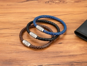 Close-up of triple-braided leather bracelets with silver magnetic clasps on wood