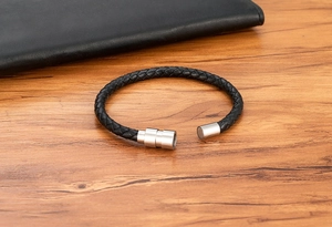 Detail of black braided leather bracelet with silver magnetic stainless steel clasp