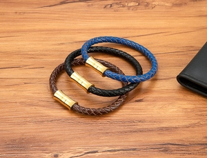 Detailed close-up of woven leather bracelets with gold magnetic clasps on a wood surface