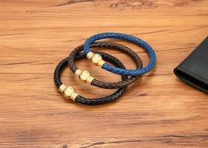 Dettaglio di bracciali in pelle intrecciata blu, marrone e nero con chiusure magnetiche oro
