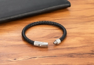 Gedetailleerde weergave van zwart gevlochten leren armband met stalen textuur sluiting