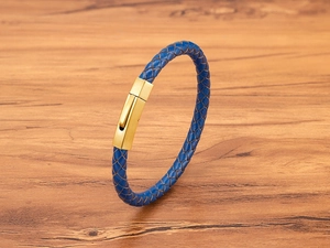 Detailed close-up of blue braided leather strap and gold brushed hexagonal clasp