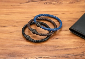 Dettaglio di tre braccialetti da uomo in pelle intrecciata con chiusura magnetica