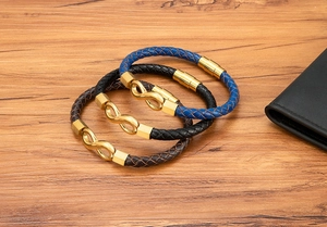 Close-up of three braided leather infinity bracelets in navy, black, and brown with gold magnetic clasps