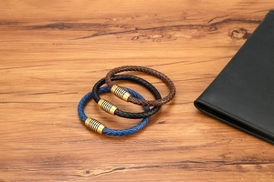 Dettaglio di bracciali in pelle intrecciata nera, blu e marrone con chiusura magnetica