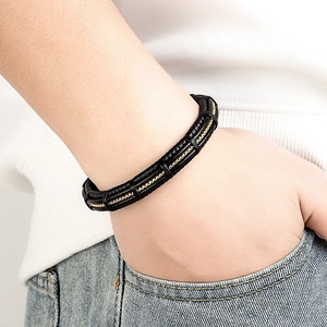 Men's minimalist black braided leather bracelet with gold chain inlay worn on wrist