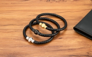 Dettaglio di bracciali in pelle intrecciata con chiusure magnetiche in oro nero e argento