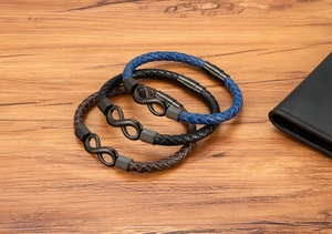 Detail of woven leather bracelets with infinity symbol and magnetic clasp on wooden table